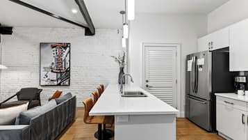 A modern kitchen with a central island, stainless steel appliances, and a white brick wall.
