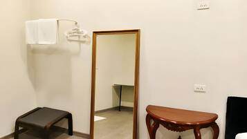 A room with a large mirror, a small stool, and a wooden table.