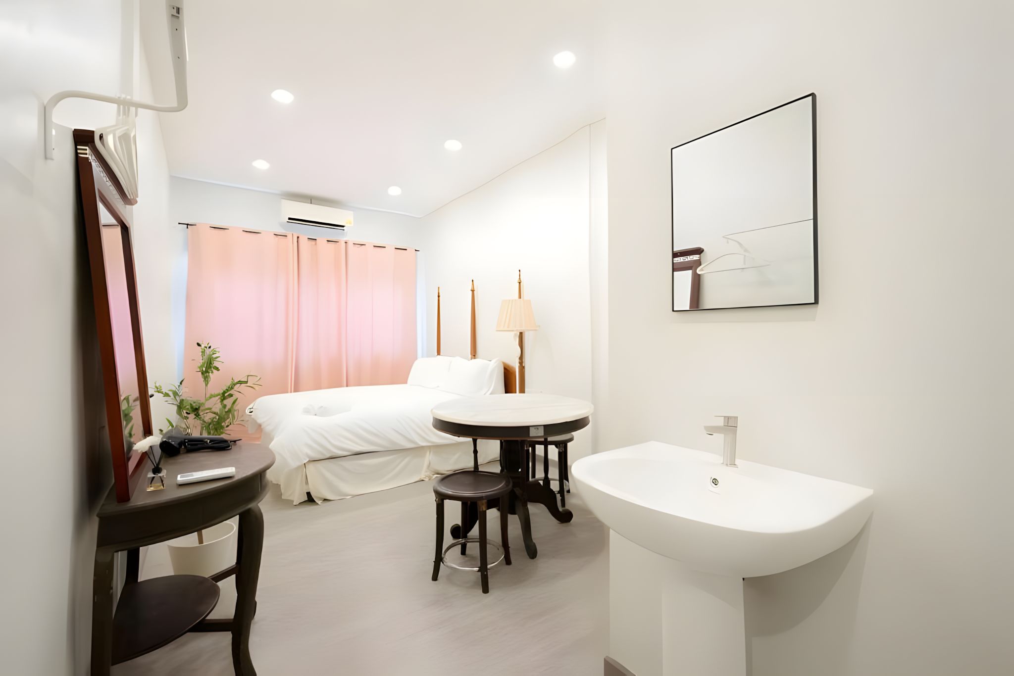 A hotel room with a bed, bedside table, lamp, and a large mirror.