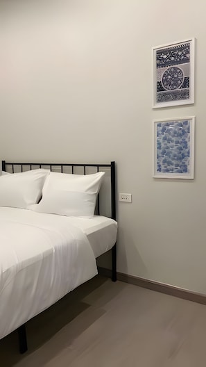 A bed with white bedding, a black metal headboard, and two framed artworks on the wall. - H room Yaowarat (Sampunthawong)