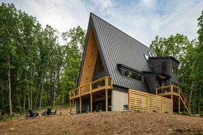 Una casa moderna con tetto a falda, terrazza in legno e un'ampia finestra.
