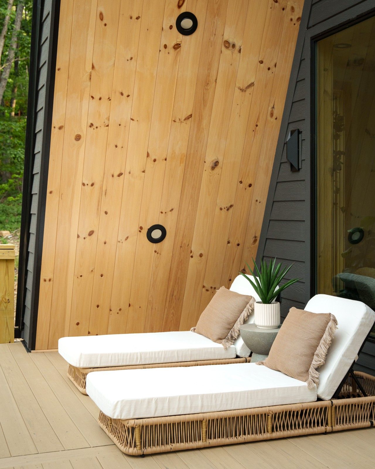 Una terraza de madera con dos sillones blancos y una planta en maceta.