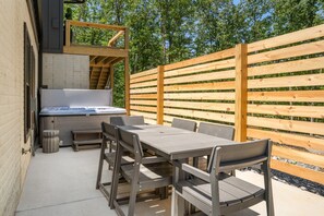 Eine Terrasse im Freien mit einem Holztisch und -stühlen, einem Whirlpool und einem Holzzaun.