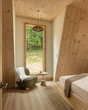 Settle into a quiet reading corner surrounded by trees—the perfect spot for coffee, a good book, and slow mountain mornings - Solhaus Shenandoah A-Frame | Park Views, Hot Tub, Theater & Game Room (Luray)