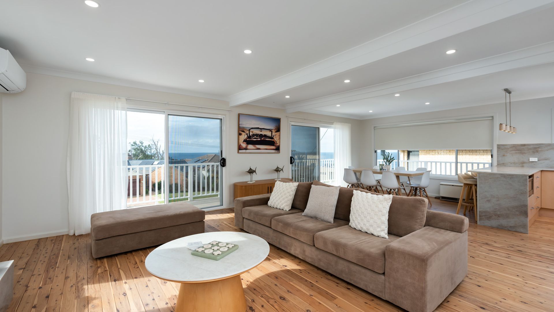 A spacious living area with a sofa, a round coffee table, and a balcony with a view.