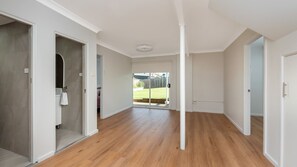 A spacious hallway with wooden flooring, white walls, and a sliding glass door leading to a backyard. - Mollymere Coastal Retreat in Mollymook Beach (Mollymook Beach)
