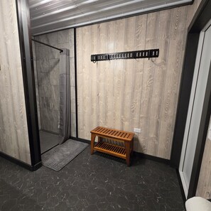 A room with a wooden wall, a bench, a shower area, and a tiled floor. - Not Your Average Driveway (Duluth)