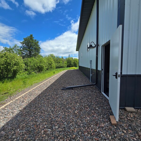 A gravel driveway leading to a building with a metal exterior and a door.