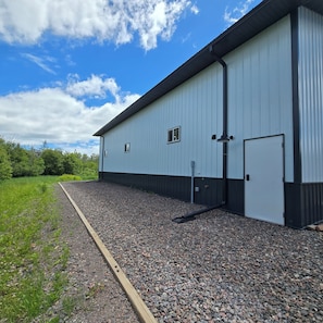 A large industrial building with a flat roof, a gravel driveway, and a metal fence.