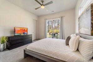 Ein Schlafzimmer mit einem Bett, einem Fernseher, einem Deckenventilator, einem Fenster und Blick ins Freie.