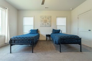 A bedroom with two beds, a ceiling fan, and a decorative wall piece. - Peaceful 4-bedroom home in charming Charlotte near Uptown (Charlotte)