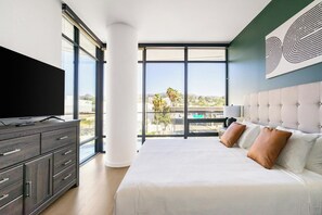 Ein modernes Schlafzimmer mit einem großen Bett, einem Fernseher und Blick auf die Stadt.