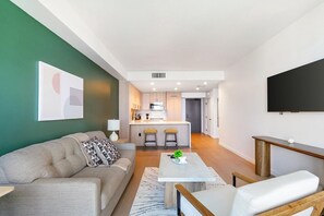 A modern living room with a sofa, a coffee table, and a TV mounted on the wall. - Landing | Incredible 1BD in Hollywood (Los Angeles)