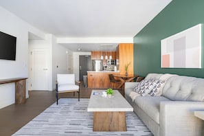 Ein modernes Wohnzimmer mit Sofa, Couchtisch und einem Essbereich mit Stühlen.