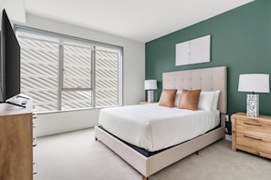 A bedroom with a bed, bedside tables, a TV, and a window with blinds. - Landing | Incredible 1BD, Gym, Rooftop Lounge (Los Angeles)