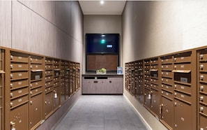 A hallway with mailboxes on both sides, a reception desk in the center, and a large window above. - Landing | Modern Studio in Hollywood (Los Angeles)