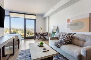 A modern living room with a sofa, coffee table, and a dining area with chairs. - Landing | Modern Studio in Hollywood (Los Angeles)