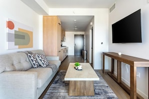 A modern living room with a sofa, coffee table, and a TV mounted on the wall. - Landing | Modern Studio in Hollywood (Los Angeles)