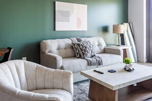 A living room with a sofa, armchair, coffee table, and a lamp. - Landing | Spectacular 1BD in Hollywood (Los Angeles)