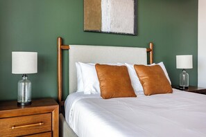 A neatly made bed with white bedding and two brown pillows, flanked by wooden nightstands with lamps. - Landing | Spectacular 1BD in Hollywood (Los Angeles)