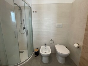 Ein modernes Badezimmer mit einer Duschkabine, einem Bidet und einer Toilette.