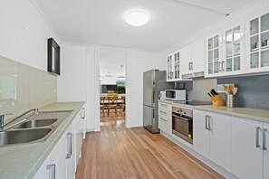 A modern kitchen with stainless steel appliances, white cabinetry, and a wooden floor. - Islander Unit 6 - Home Beach (Point Lookout)