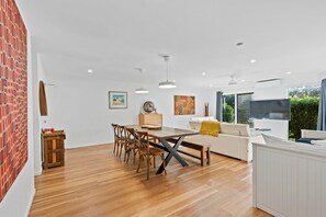 A modern interior with a dining area, a sofa, and a TV. - Islander Unit 6 - Home Beach (Point Lookout)