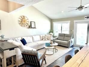 Ein Wohnzimmer mit Sofa, Sessel, Couchtisch und Esstisch.