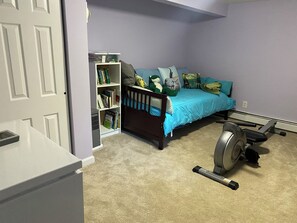 Une chambre à coucher avec un lit, une bibliothèque, un tapis de course et une porte.