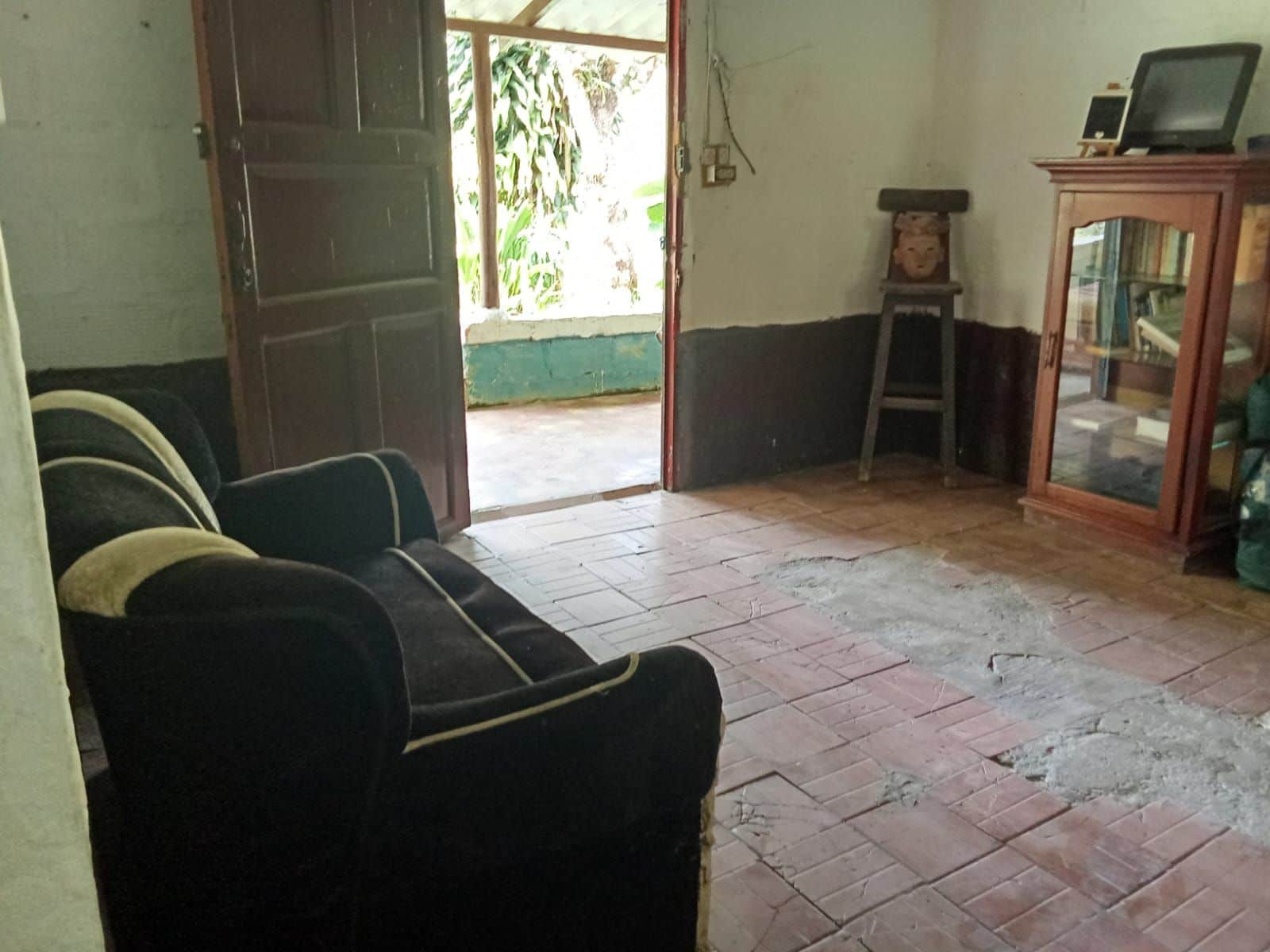 A room with a sofa, a television on a cabinet, and a door leading outside.