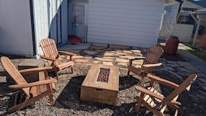 Un patio con sillas Adirondack y una chimenea.