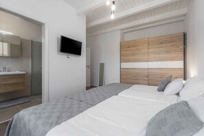 Une chambre moderne avec un lit, une télévision et une armoire.