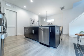 A modern kitchen with a central island, stainless steel appliances, and a pendant light. - Fantastic 4-bedroom house near Uptown Charlotte - sleeps up to 14 (Charlotte)
