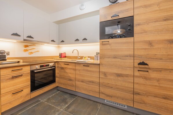 Una cocina moderna con armarios de madera, horno empotrado y microondas.