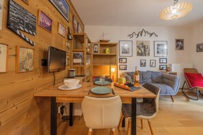 Una sala acogedora con una mesa de comedor de madera, un sofá y un televisor montado en la pared.