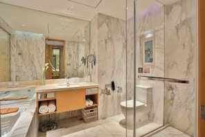 A modern bathroom with a marble vanity, a glass shower enclosure, and a large mirror.