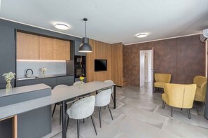 A modern kitchen with a built-in oven, a dining area with a table and chairs, and a TV mounted on a wooden wall. - Villa Villa Ana Tinjan (691177,ANATINJAN) (Tinjan)