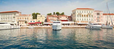 A marina with several yachts docked, surrounded by buildings with classic architecture.
