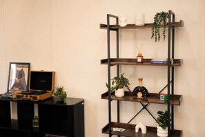 A black speaker cabinet with a vinyl record player, a framed picture, and a small potted plant. - Boutique Property | Pool, Tennis & Jetty (Bundall)