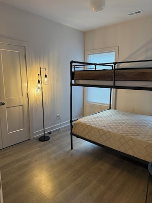 A room with a bunk bed, a standing floor lamp, and a door. - Spacious 4-bedroom house across from Pickleball Park near Uptown (Charlotte)