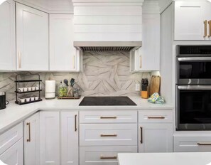 A modern kitchen with white cabinetry, a black countertop, and stainless steel appliances.