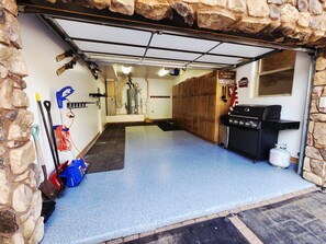 A garage with a stone wall, a water heater, a grill, and various tools. - Black Diamond Lakeview Retreat, Ski In/Out + Hot Tub (Brian Head)