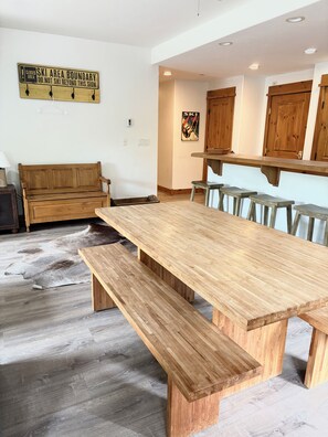 Une table à manger en bois avec des bancs, un banc en bois, une enseigne fixée au mur et un meuble en bois.
