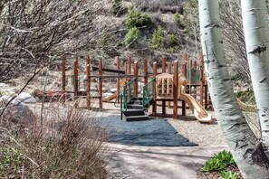 A playground with a slide, climbing structures, and a green staircase leading up to the play area. - Cozy Arrowhead Condo Just Steps from the Ski Lift and Pool (Edwards)