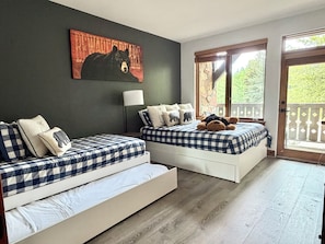 A bedroom with two beds, a large window, and a bear-themed artwork on the wall. - Cozy Arrowhead Condo Just Steps from the Ski Lift and Pool (Edwards)