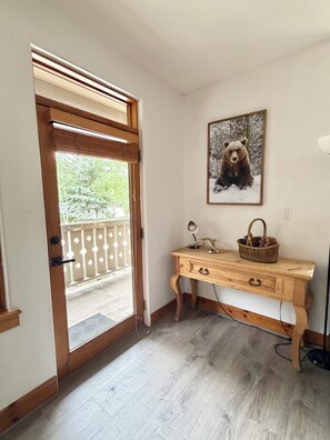 A room with a wooden desk, a framed bear picture, and a door leading outside. - Cozy Arrowhead Condo Just Steps from the Ski Lift and Pool (Edwards)