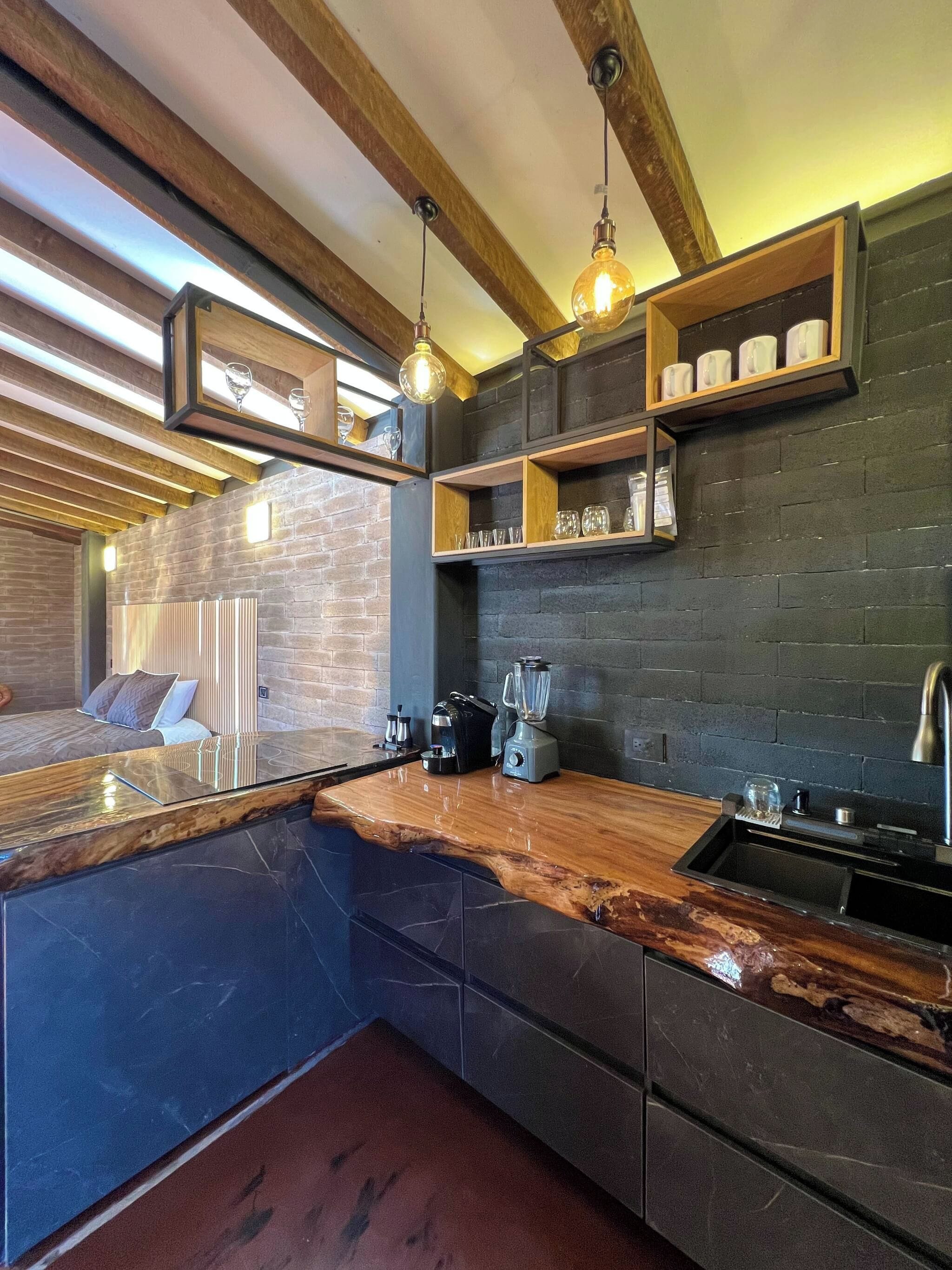 A modern kitchen with a marble countertop, wooden beams, and built-in shelves.