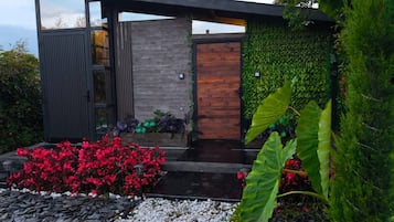 A modern house with a wooden door, a stone wall, and a green wall with plants.