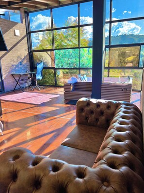 A modern room with a large window, a leather sofa, a desk, and a chair. - Private Cabin to Enjoy Luxury and Comfort (Rionegro)