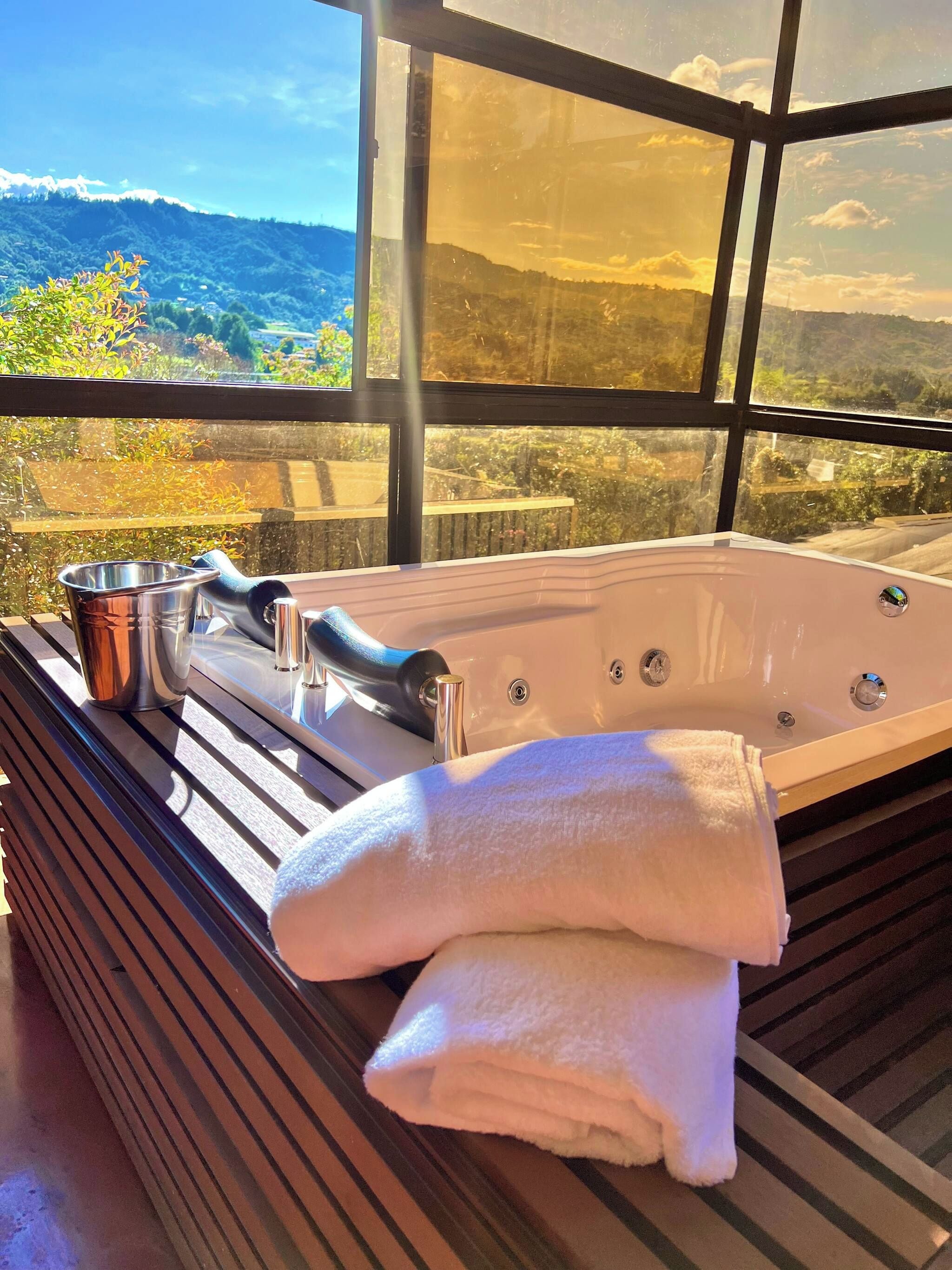 Un espacio de spa con una bañera grande, un cubo de metal y dos toallas.